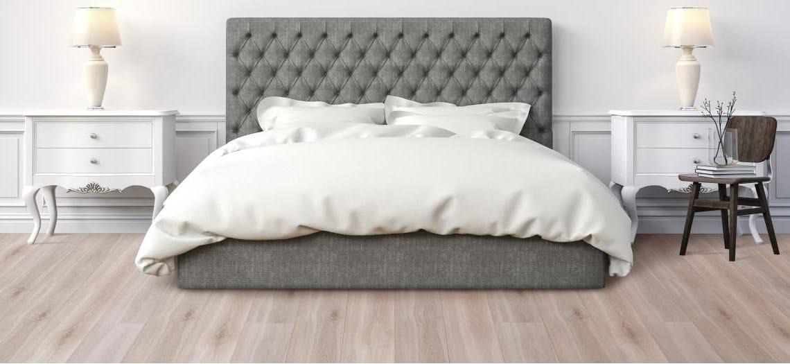 Slaapkamer met een lichte houten vloer en een gestoffeerd bed